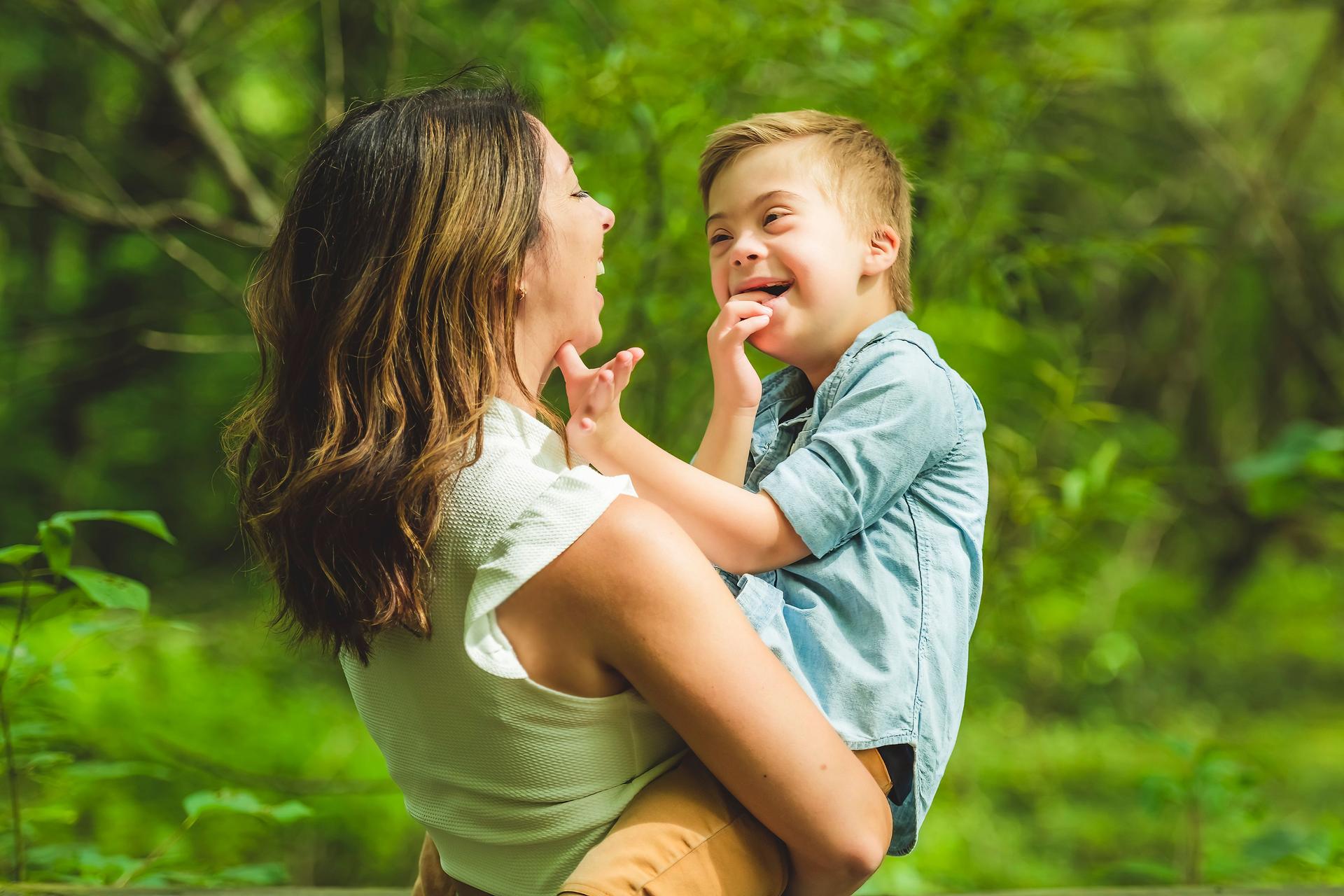 Portrait of a little boy with down syndrome while playing in a park with his mother
